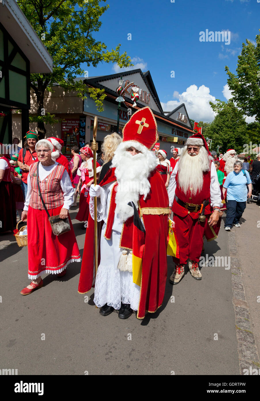Klampenborg, Denmark. 20th July, 2016. Santas, elves and Santa’s wives parade between the competitions at the World Santa Claus Congress. For more than 50 years Santas from around the world have come to hold this 3-days congress at Bakken, the amusement park in the Deer Park just north of Copenhagen. The programme on this last day of congress includes a pentathlon in the summer heat among  Santas from more than ten countries, parades, entertainments, etc. The Santa with the crozier and the mitre-like hat is from Germany. Credit:  Niels Quist/Alamy Live News Stock Photo