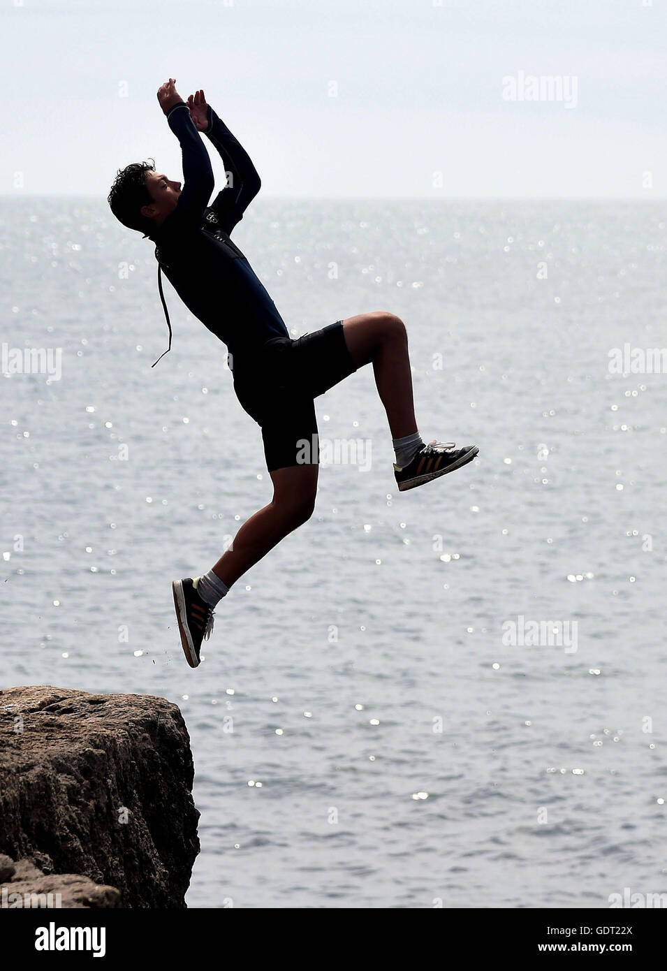 Youngsters cool off by tombstoning off the rocks at Portland Bill, Dorset, UK Stock Photo