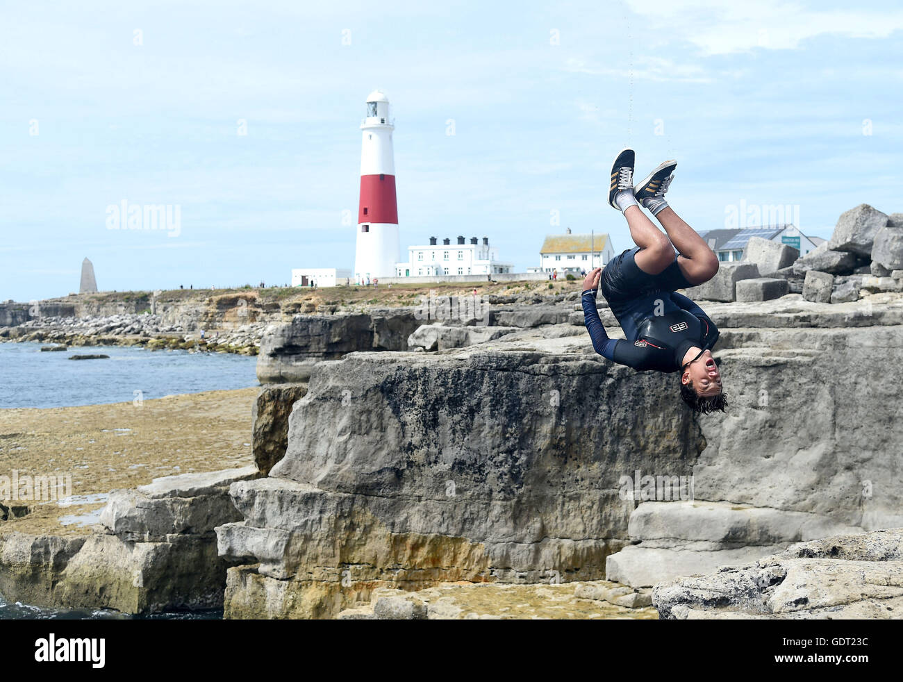 Youngsters cool off by tombstoning off the rocks at Portland Bill, Dorset, UK Stock Photo