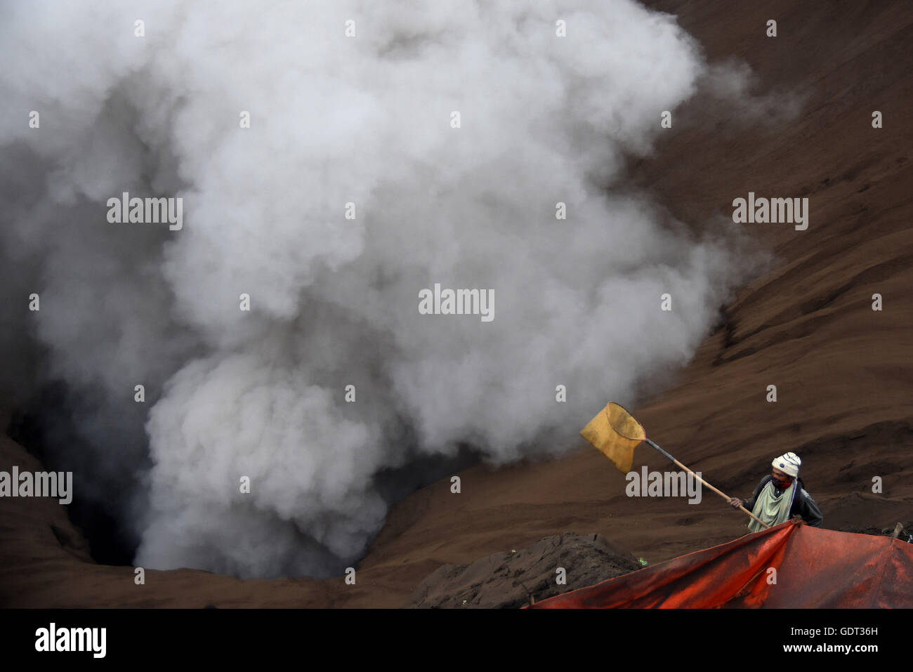 Bromo, Indonesia. 21st July, 2016. A Tenggerese worshipper throws chickens and vegetables for an offering of Mount Bromo during the Yadnya Kasada Festival at crater of Mount Bromo on July 21, 2015 in Probolinggo, East Java, Indonesia. The festival is the main festival of the Tenggerese people and lasts about a month. On the fourteenth day, the Tenggerese make the journey to Mount Bromo to make offerings of rice, fruits, vegetables, flowers and livestock to the mountain gods by throwing them into the volcano's caldera. Credit:  Yuli Seperi/Alamy Live News Stock Photo