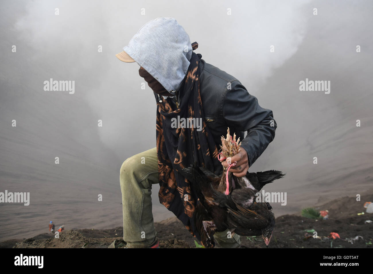 Probolinggo, East Java, Indonesia. 21st July, 2016. A Tenggerese worshipper throws chickens and vegetables for an offering of Mount Bromo during the Yadnya Kasada Festival at crater of Mount Bromo. The festival is the main festival of the Tenggerese people and lasts about a month. On the fourteenth day, the Tenggerese make the journey to Mount Bromo to make offerings of rice, fruits, vegetables, flowers and livestock to the mountain gods by throwing them into the volcano's caldera. © Sijori Images/ZUMA Wire/Alamy Live News Stock Photo