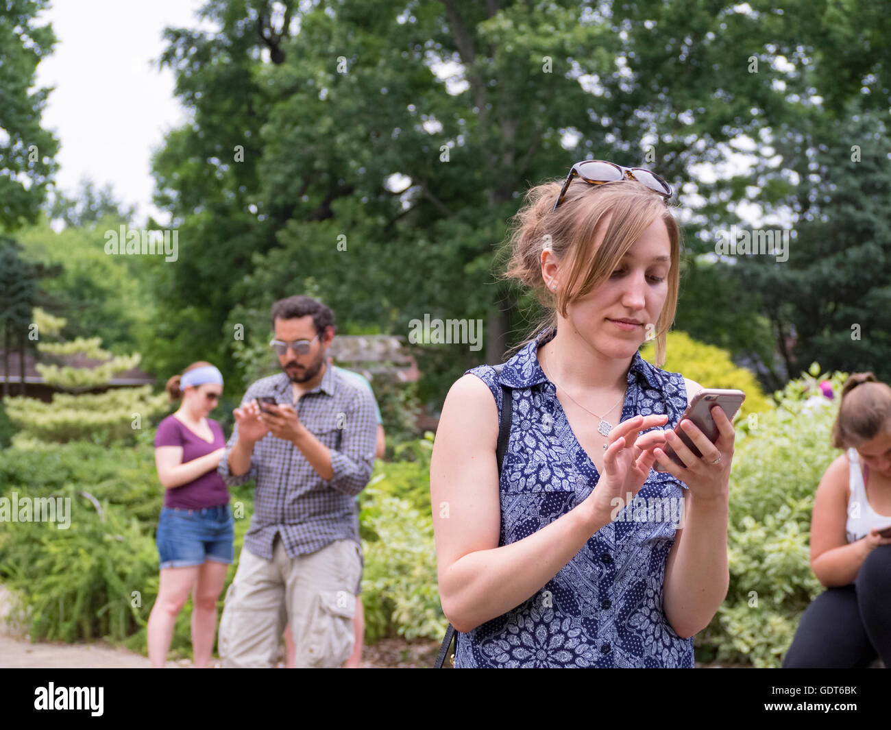 Columbus, Ohio, USA, 21 July 2016: Millennials both a young man and young women play Pokemon Go at the Park of Roses. Pokemon Go is a location based augmented reality mobile game developed by Niantic Labs using the popular Nintendo video game action figures Credit:  2016 Marianne A. Campolongo/Alamy Live News. Stock Photo