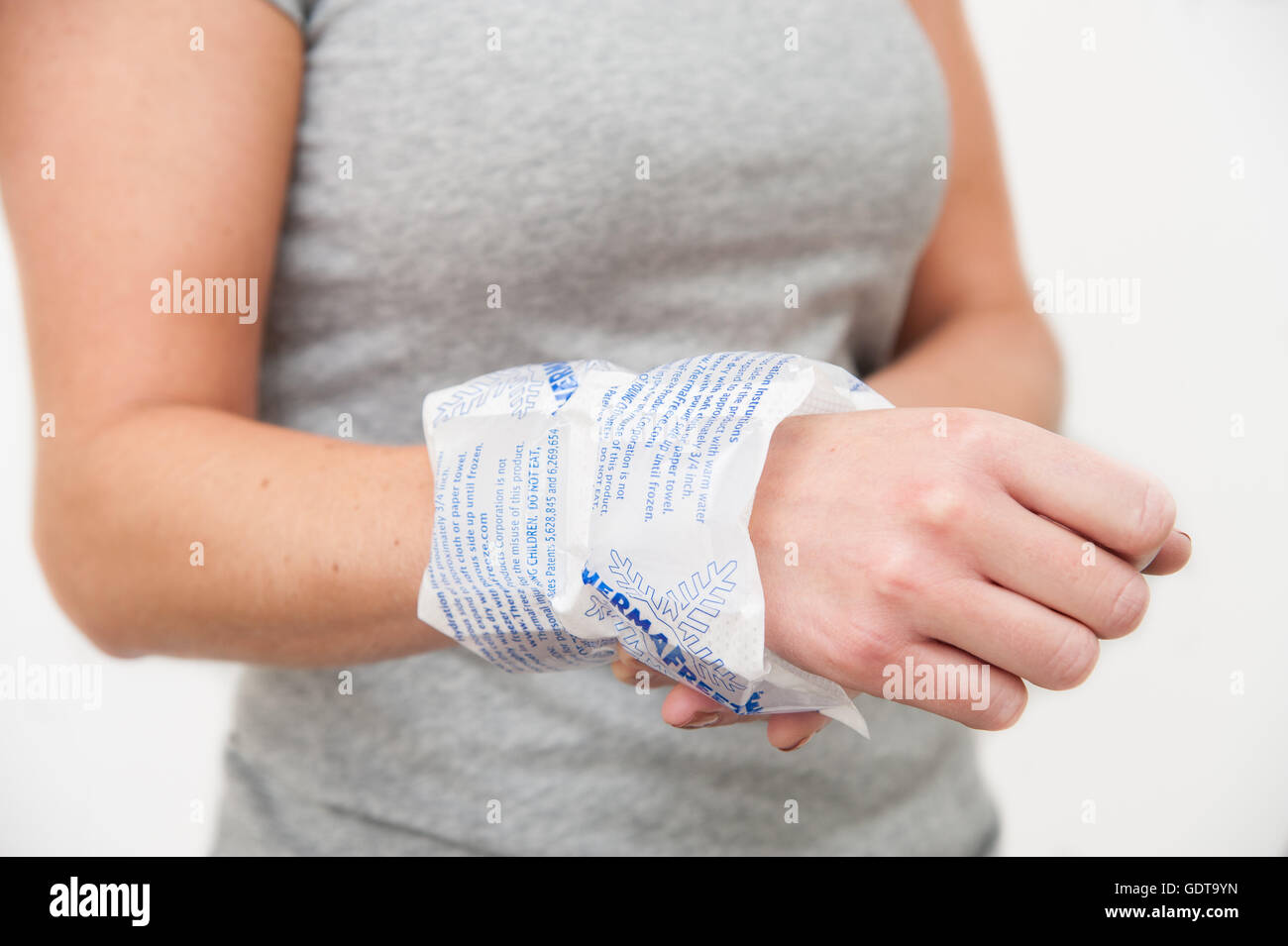 Female holding a Thermafreeze Ice Pack on her wrist to help with pain and discomfort Stock Photo