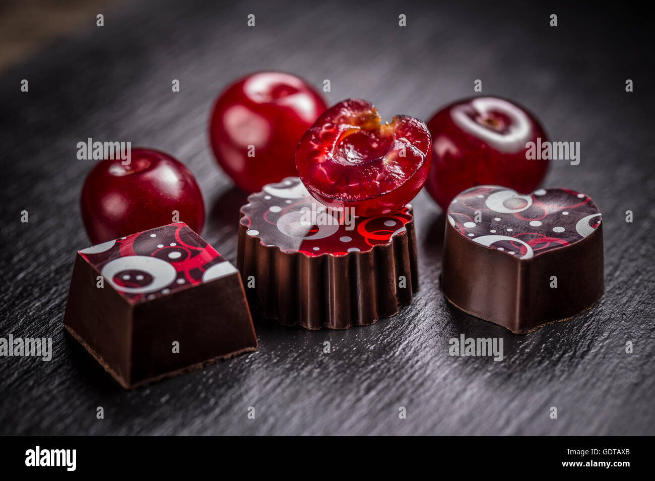 Truffle chocolate candies with cherry on black slate background Stock Photo