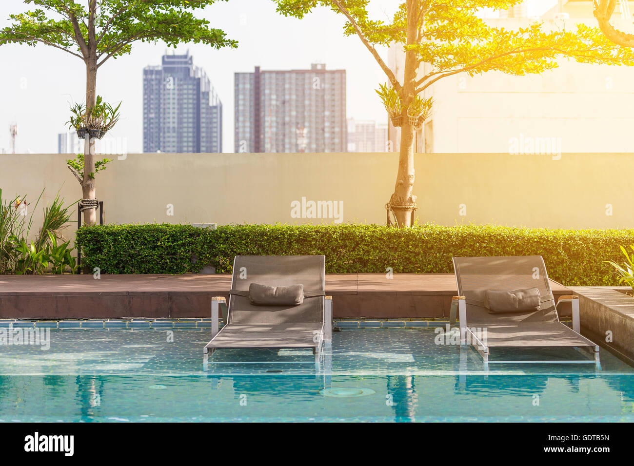 Two beach seats putting on edge of swimming pool with soft orange
