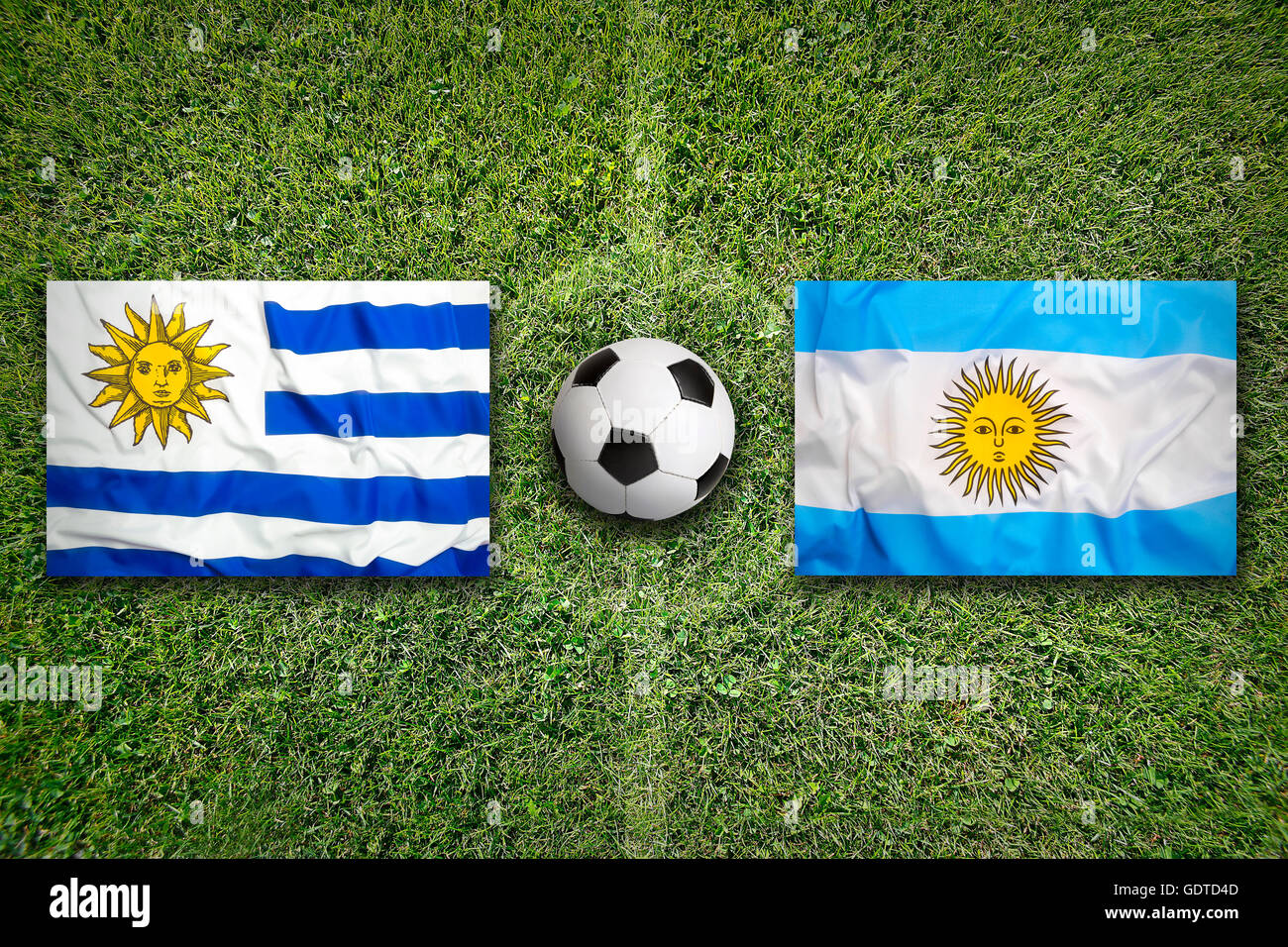 Uruguay vs. Mexico flags on green soccer field Stock Photo