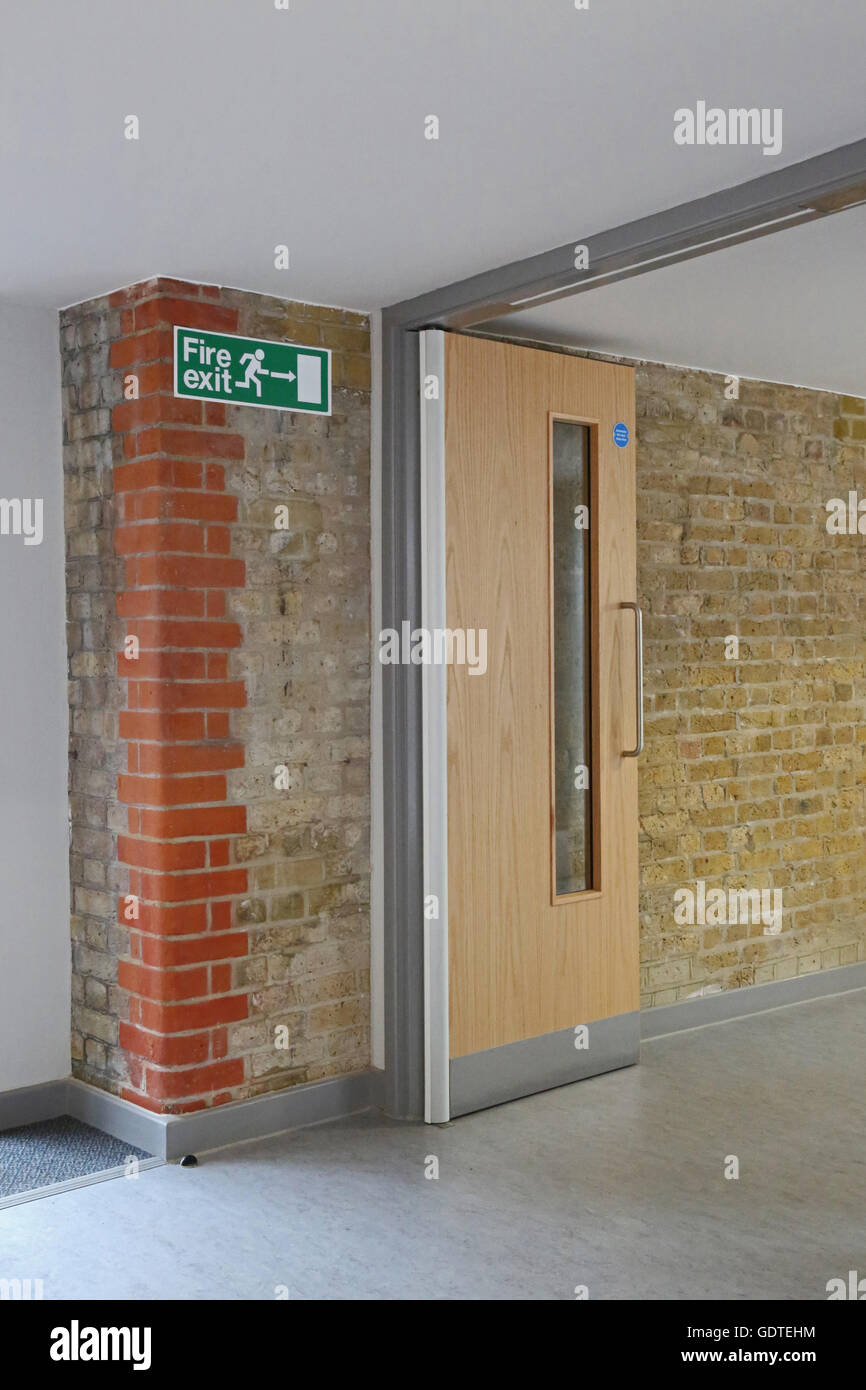 Modern fire door in a new extension to a Victorian school. New door adjoins original brickwork and features latest trap-free hinges Stock Photo
