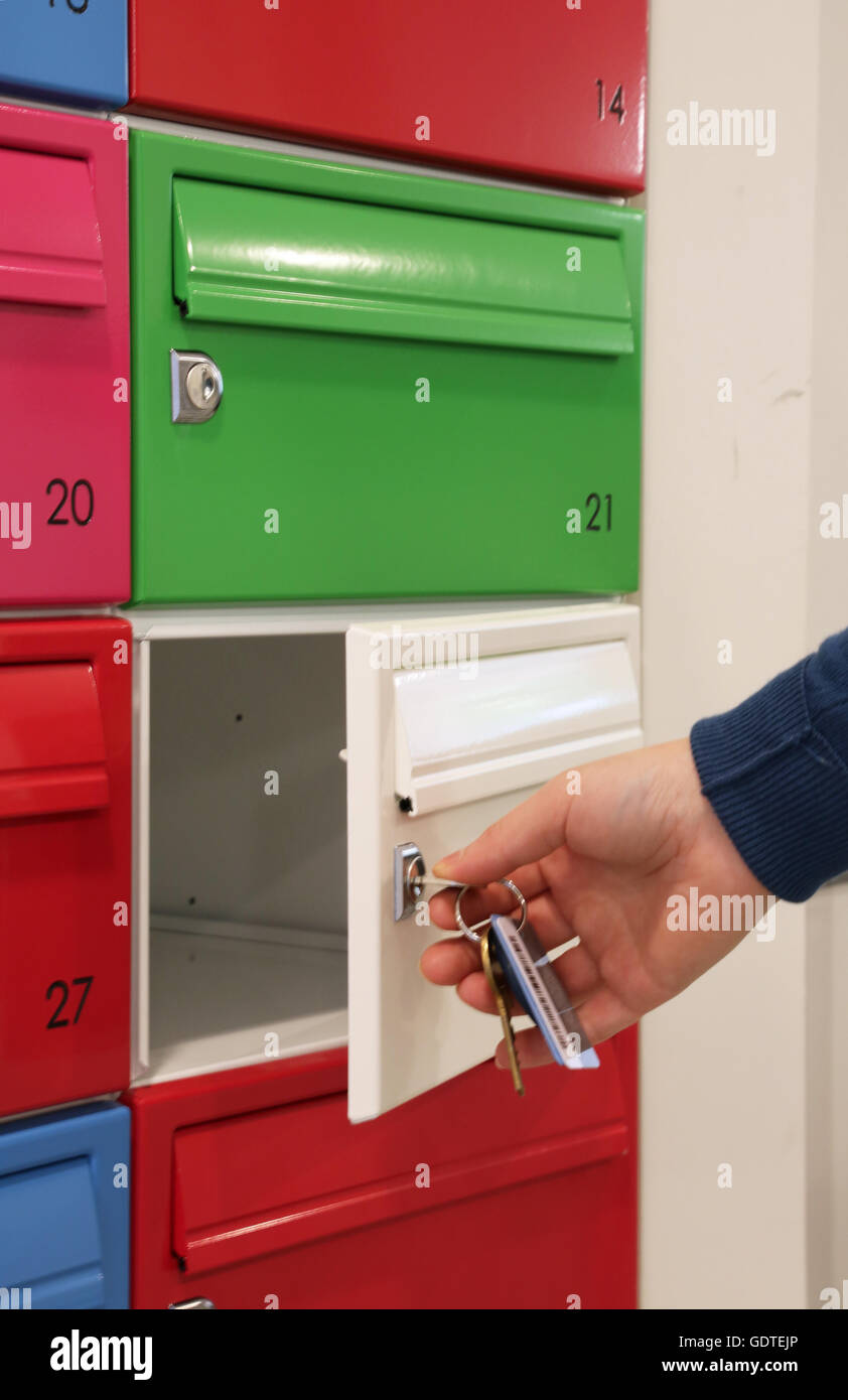 A resident opens/closes a mail boxe in the lobby of a new, trendy apartment block in Deptford, south east London, UK Stock Photo