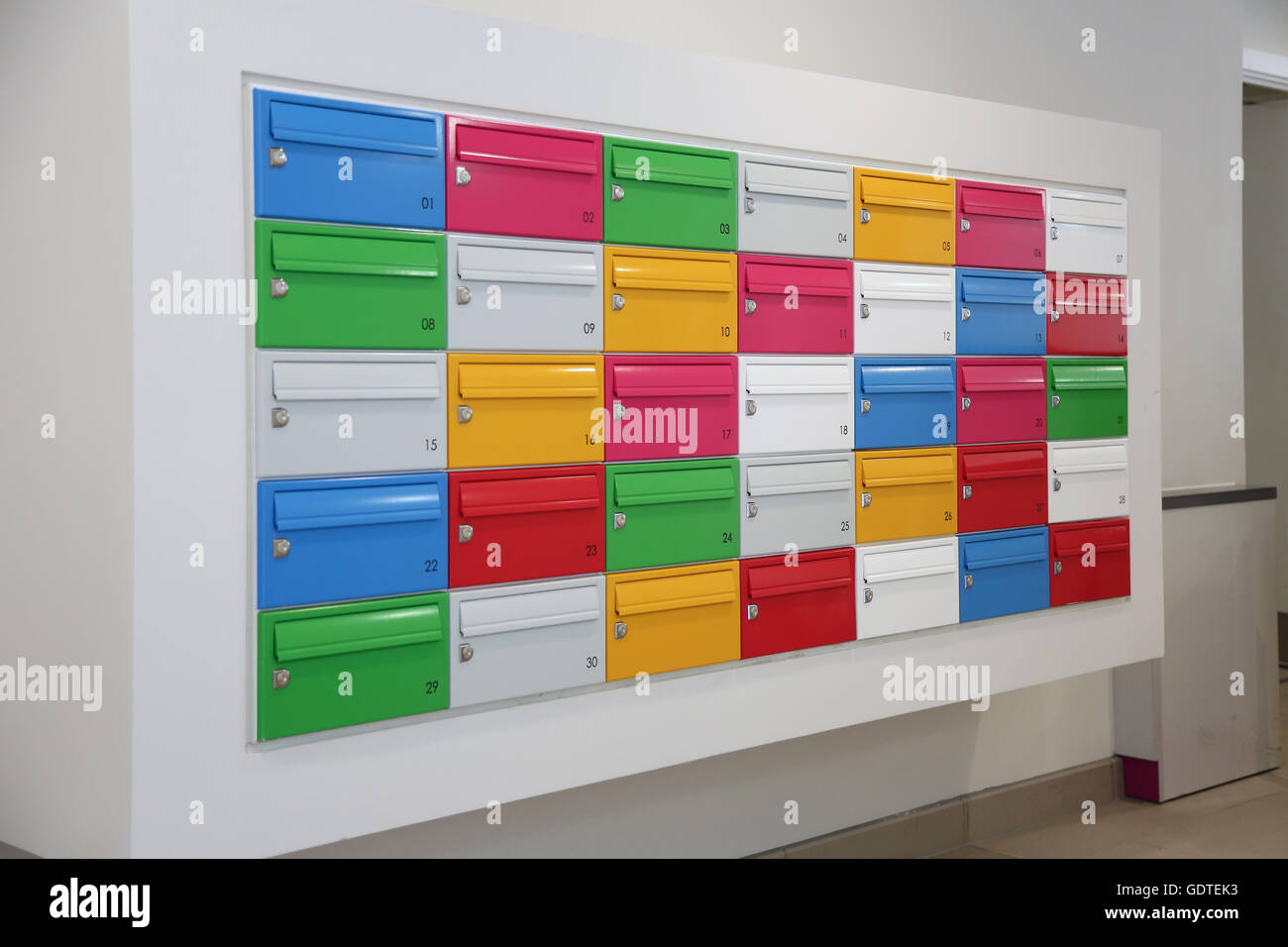 Multi-coloured mail boxes in the lobby of a new, trendy apartment block in Deptford, south east London, UK Stock Photo