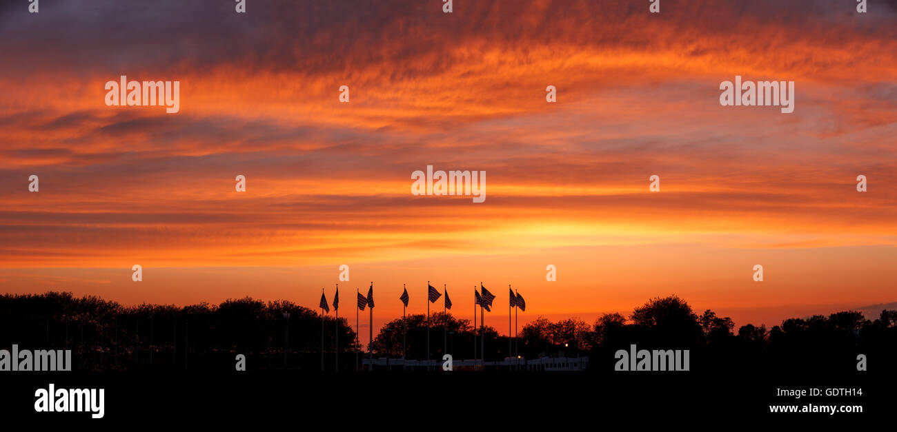 Sunset on Flag Plaza, Liberty State Park, New Jersey. U.S. Flags standing under a glowing cloudy sky lit by the setting sun Stock Photo