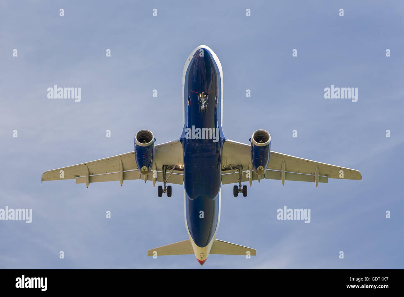 Airplane landing against blue sky Stock Photo - Alamy