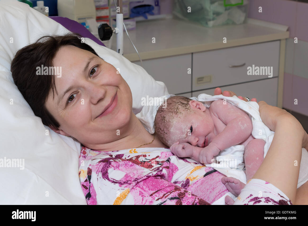 Happy mature woman, mother, with newborn baby immediately after delivery. Stock Photo