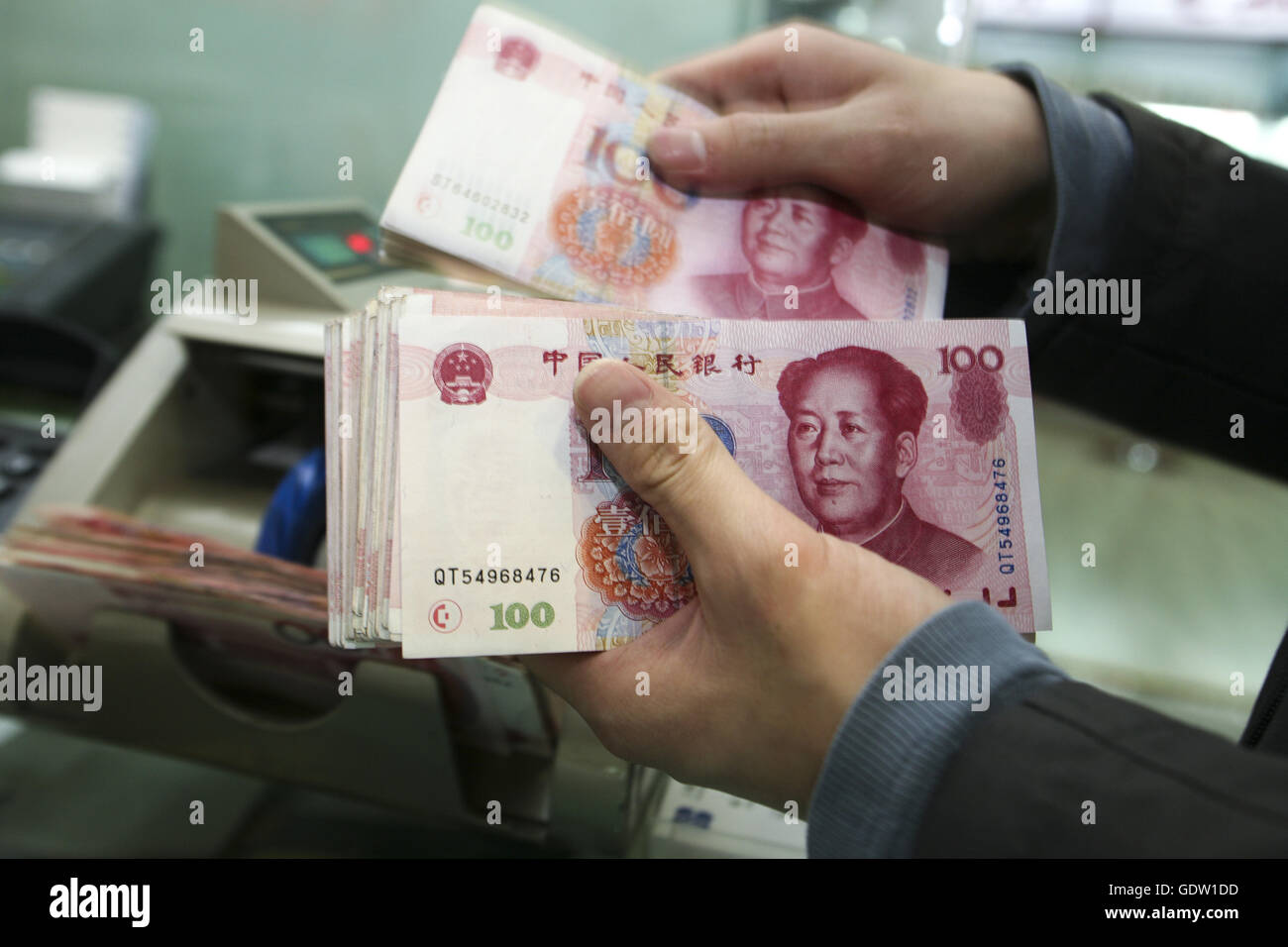 A cashier verify one hundred bank note of Chinese yuan or Renminbi Stock Photo