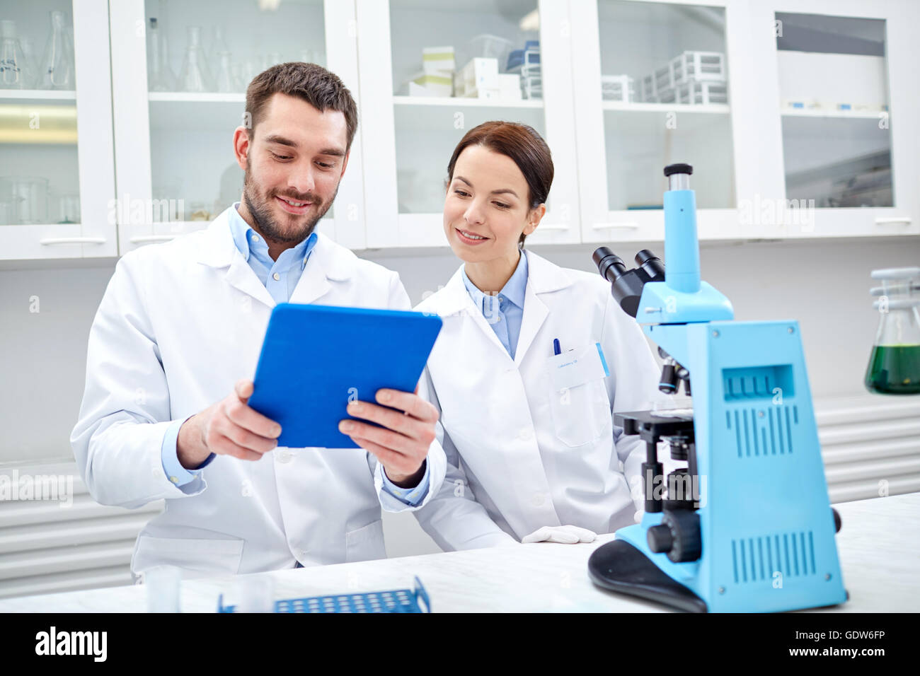 scientists with tablet pc and microscope in lab Stock Photo - Alamy