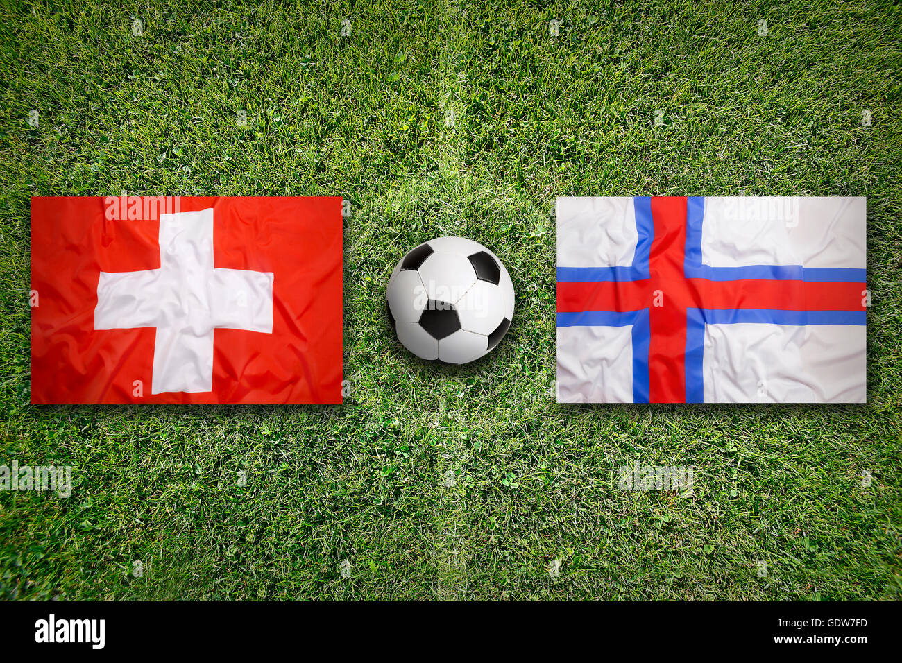 Switzerland vs. Faeroe Islands flags on green soccer field Stock Photo