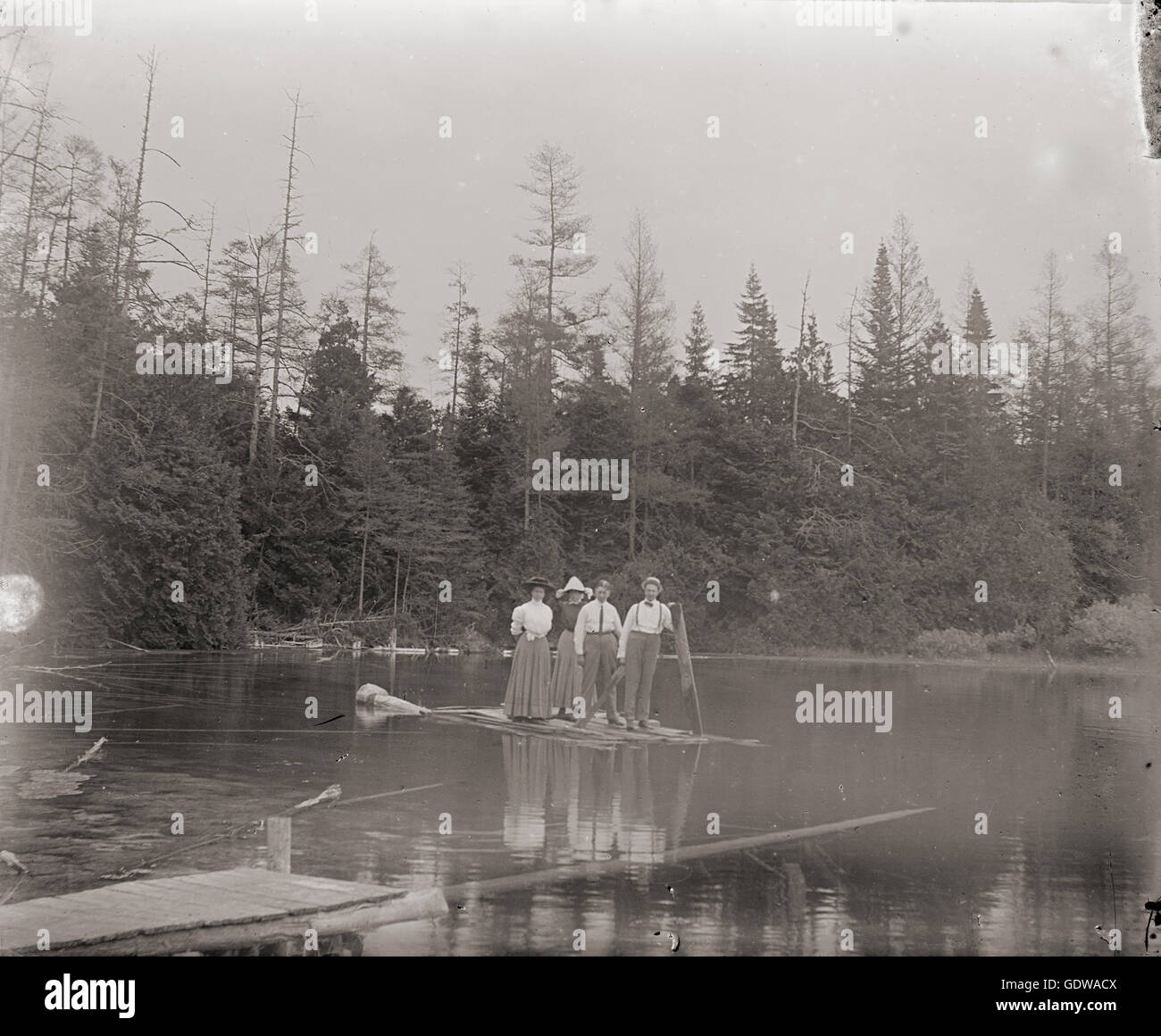 Antique c1900 late Victorian photograph, two men and two women on a raft in a pond. Location: Michigan, USA. SOURCE: ORIGINAL PHOTOGRAPHIC NEGATIVE. Stock Photo