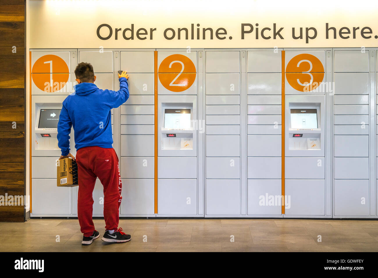 Man closing an ecommerce locker after picking up a package he ordered online Stock Photo