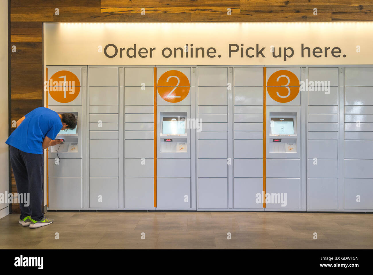 Man scanning his smartphone at an ecommerce locker to get a package he ordered online Stock Photo