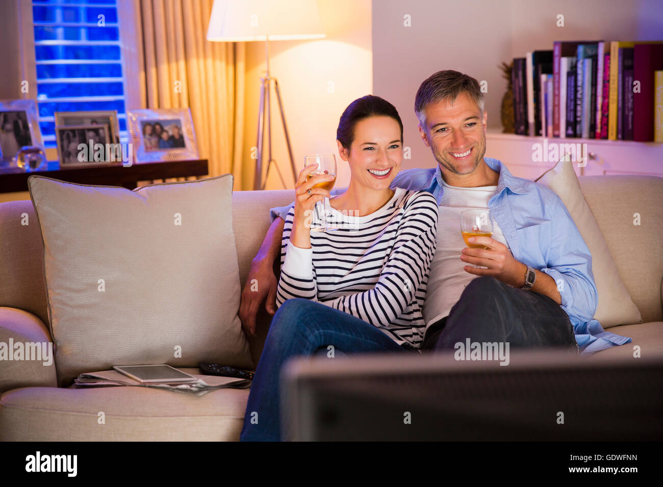 Couple drinking wine and watching TV in living room Stock Photo