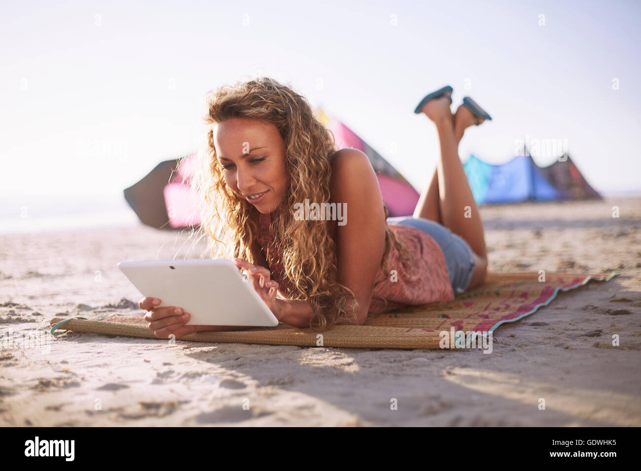 Woman reading digital tablet on beach mat Stock Photo