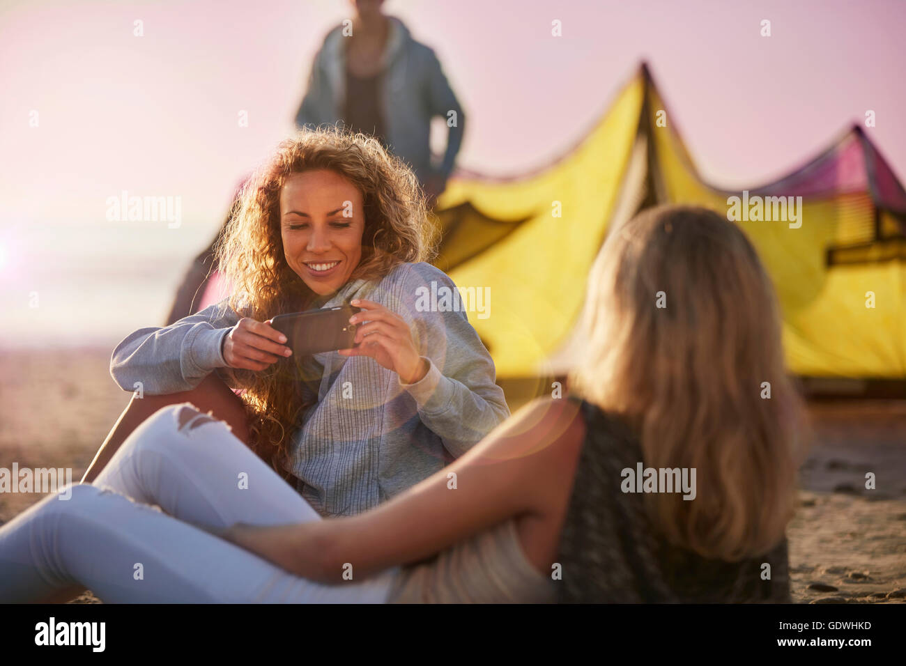 Women using camera phone on beach Stock Photo