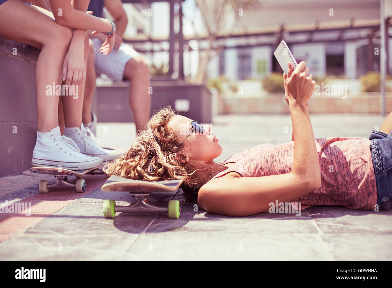 Young woman with digital tablet laying on skateboard Stock Photo