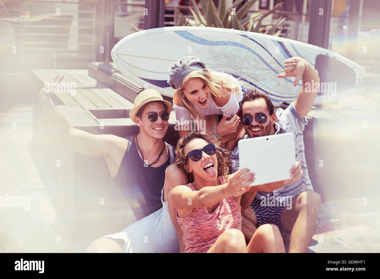 Playful young friends taking selfie in front of surfboard with digital tablet Stock Photo