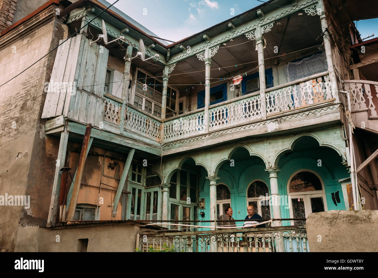 Tbilisi, Georgia - May 19, 2016: Two Men Talking While Standing On The Balcony Of An Old House In The Old Part Of Tbilisi - The Stock Photo