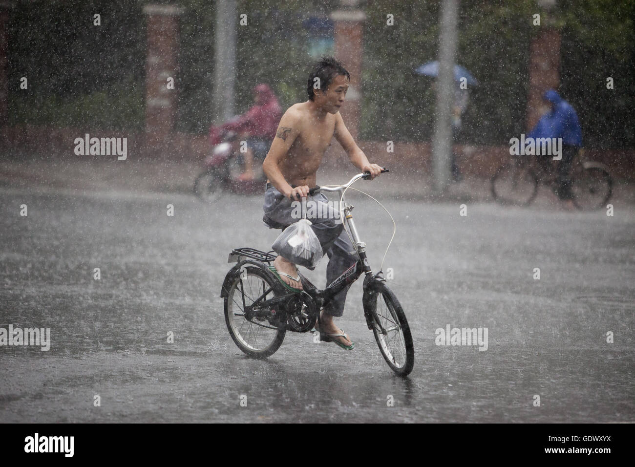 Man rides bicycle under rain hi-res stock photography and images - Alamy