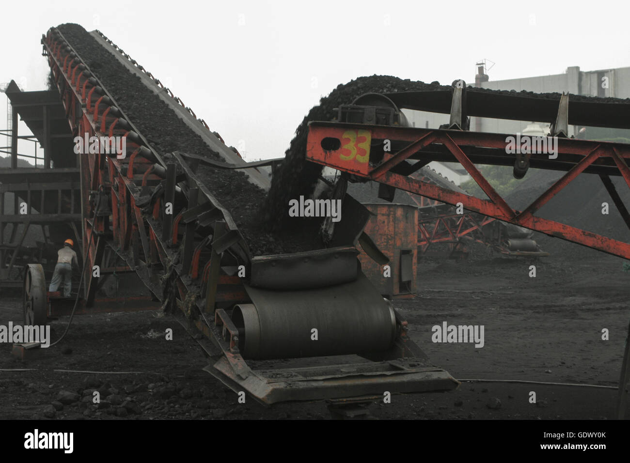 Worker manages coal sand at a harbour Stock Photo - Alamy