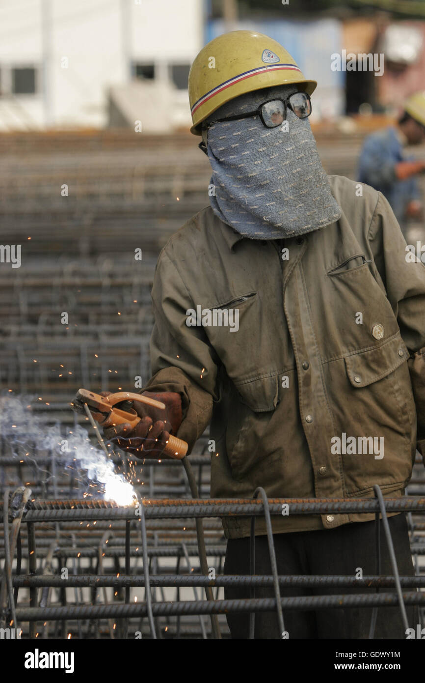A worker wields a steel frame at a construction site Stock Photo
