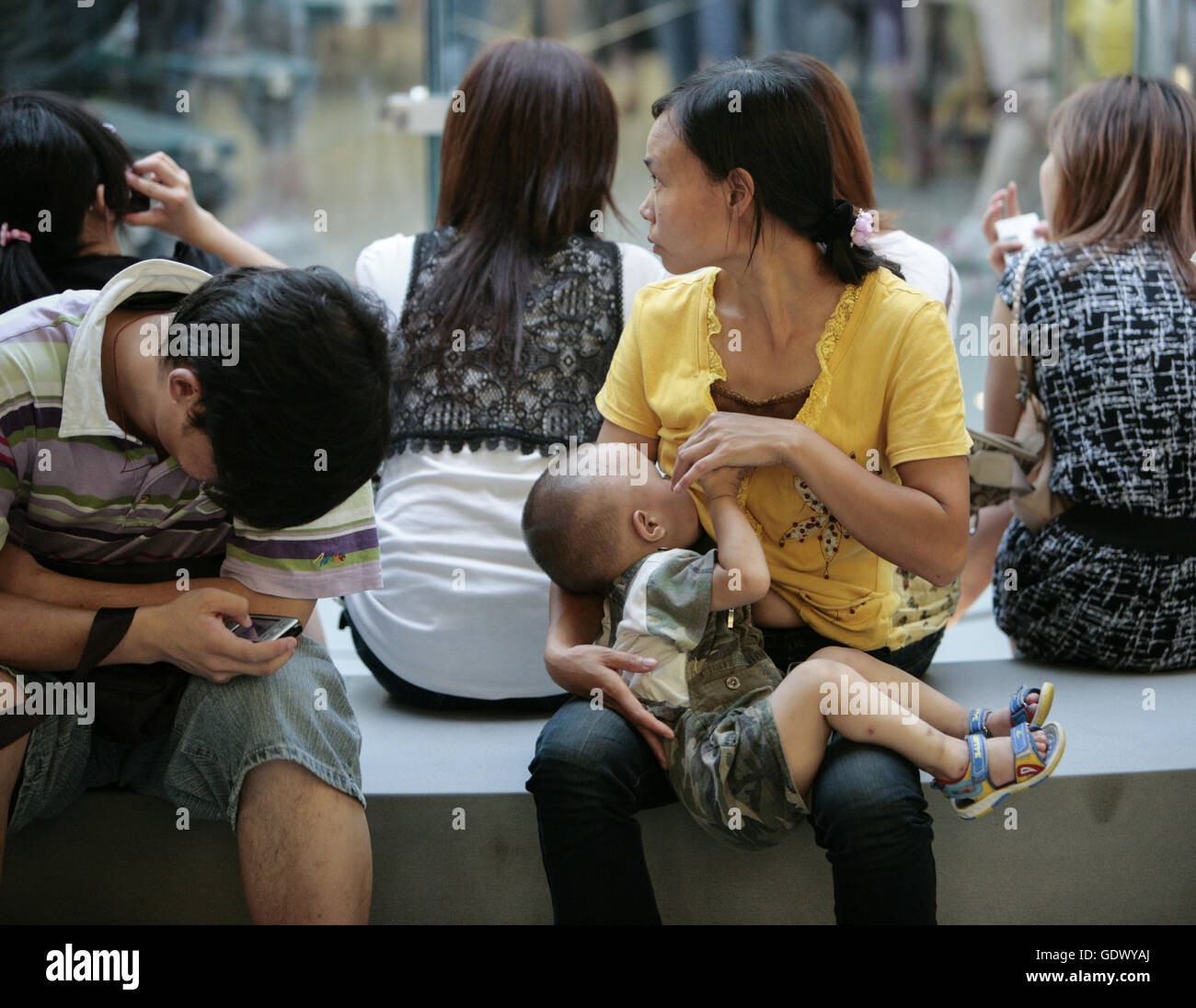 https://c8.alamy.com/comp/GDWYAJ/a-woman-breastfeeding-a-kid-in-a-mall-GDWYAJ.jpg