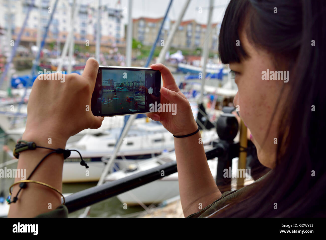 Woman taking a photo of boats in harbour with camera phone Stock Photo