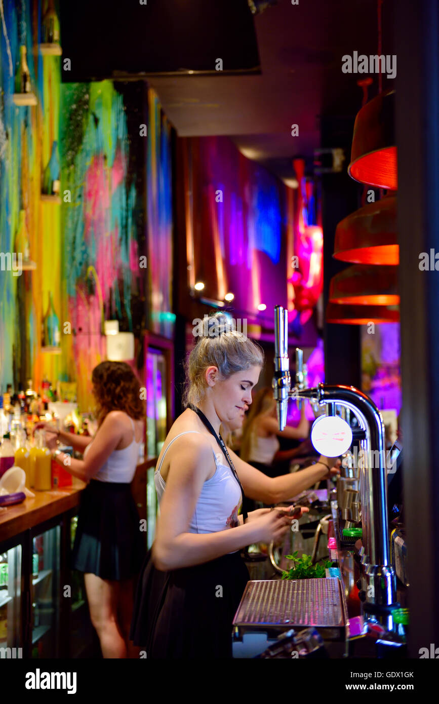 Bar, Steinbeck & Shaw, Bristol, decorated in very colourful way with young woman serving beer, UK Stock Photo