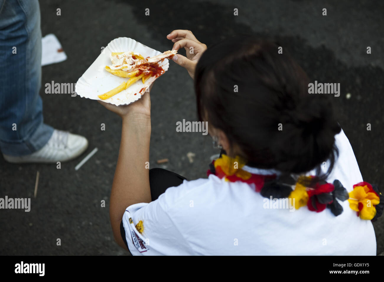 Woman eats fries on the German Fan Mile (Fanmeile) at the World Cup in Berlin, Germany, 2010 Stock Photo