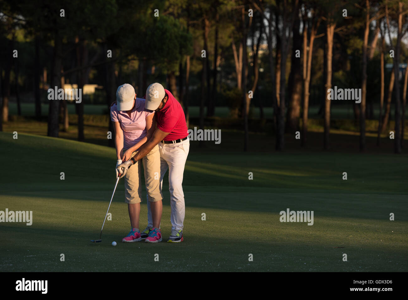 male golf instructor teaching female golf player, personal trainer giving lesson on golf course