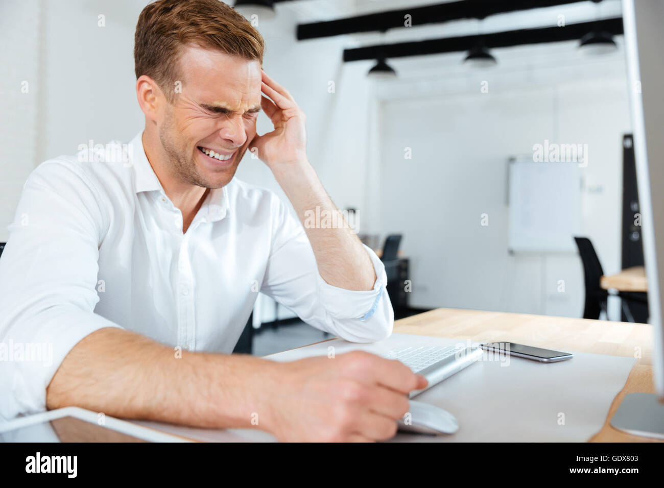 Stressed tensed young businessman suffering from headache in office Stock Photo