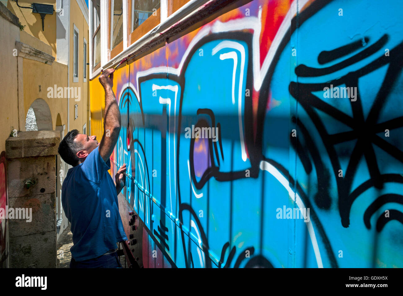 Man paints over a graffiti in Lisbon, Portugal, 2014 Stock Photo