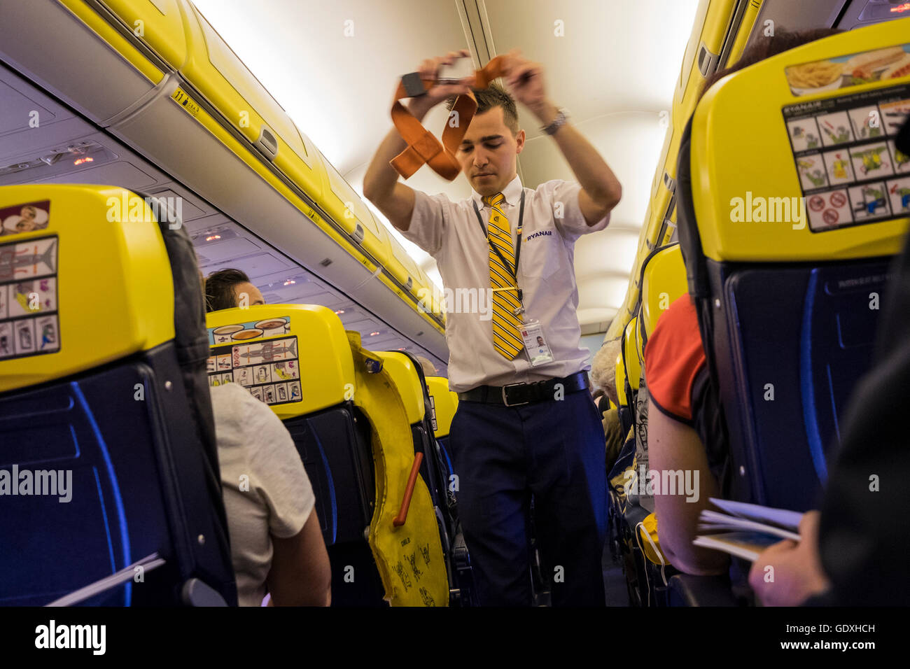 Male Ryanair cabin crew demonstrating safety procedures prior to departure, Stock Photo