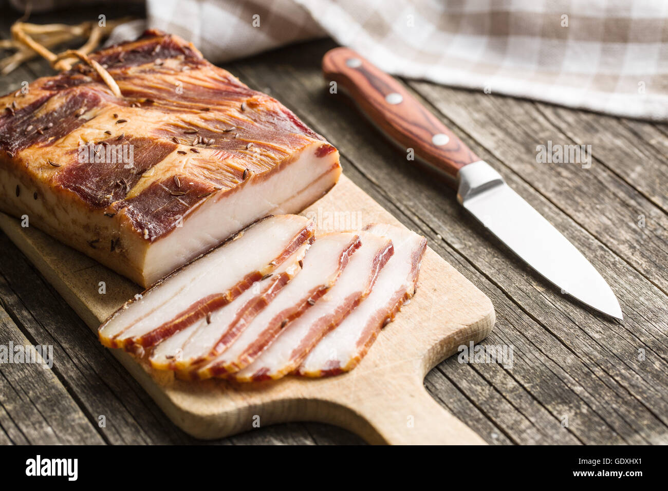 Sliced smoked bacon on old wooden table. Stock Photo