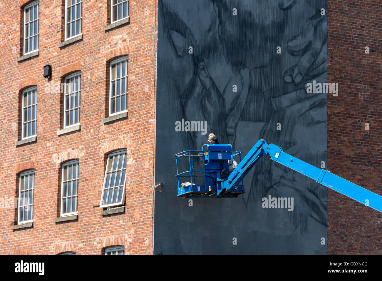 Street artist Faith47 at work on the mural '722-481 BC' on the side of Brownsfield Mill, Ancoats, Manchester, England, UK Stock Photo