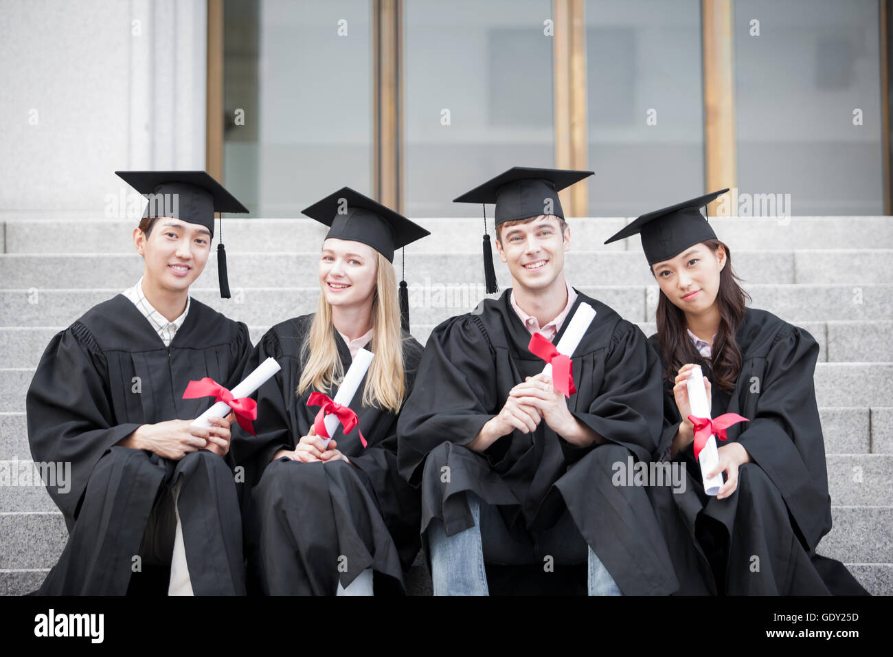 Four smiling college graduates with their certifications Stock Photo