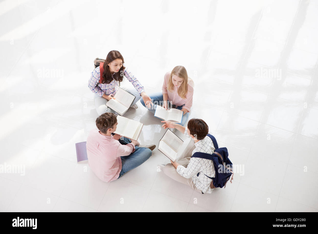 High angle view of college students with books sitting in circle Stock Photo