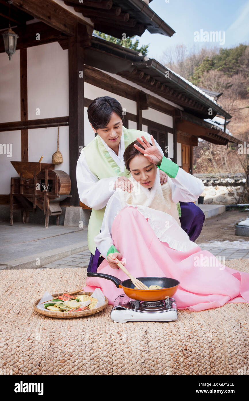 Loving husband giving a massage to his wife cooking Stock Photo
