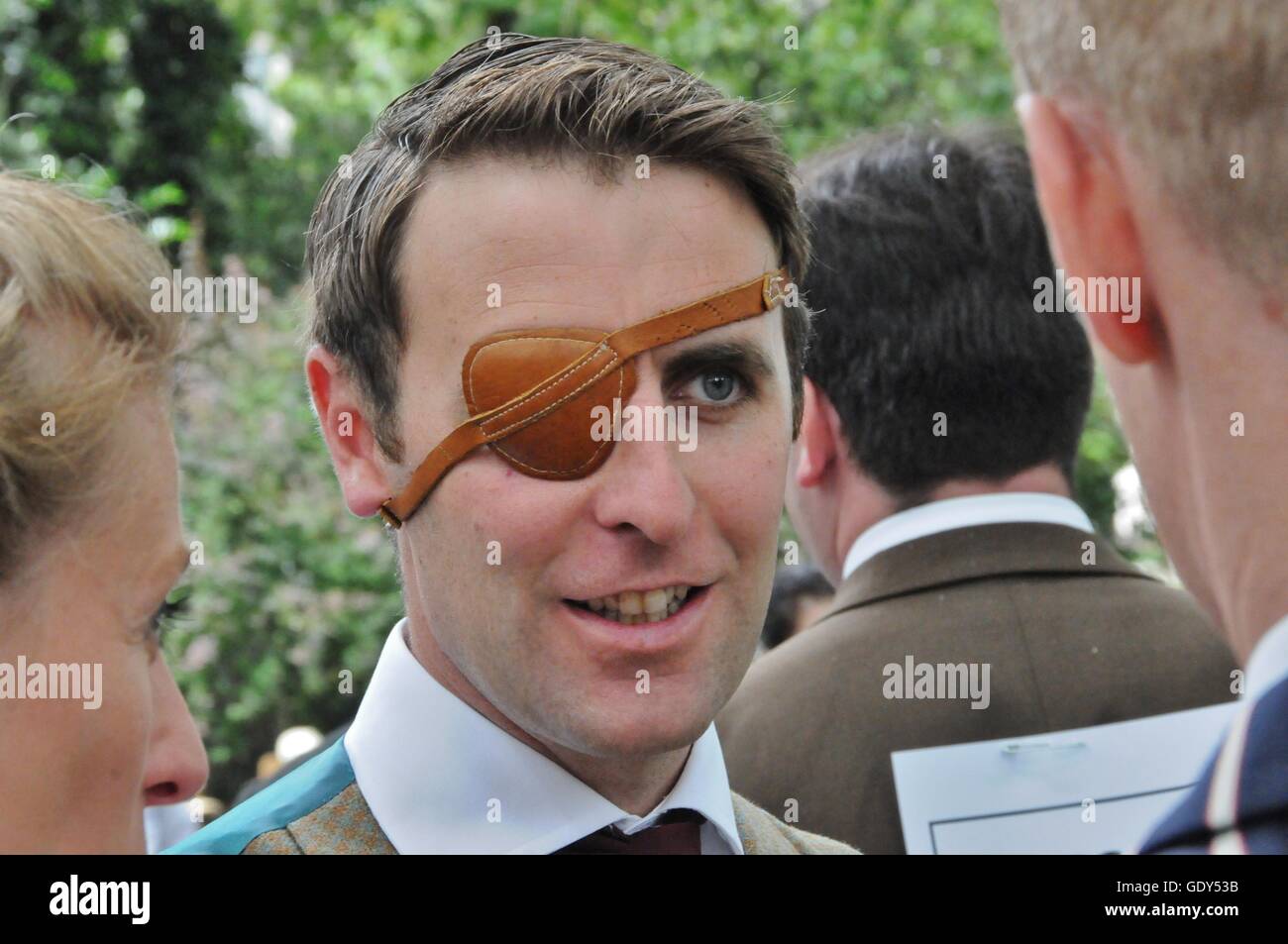 A man with an eye patch, talking to his friends. Stock Photo