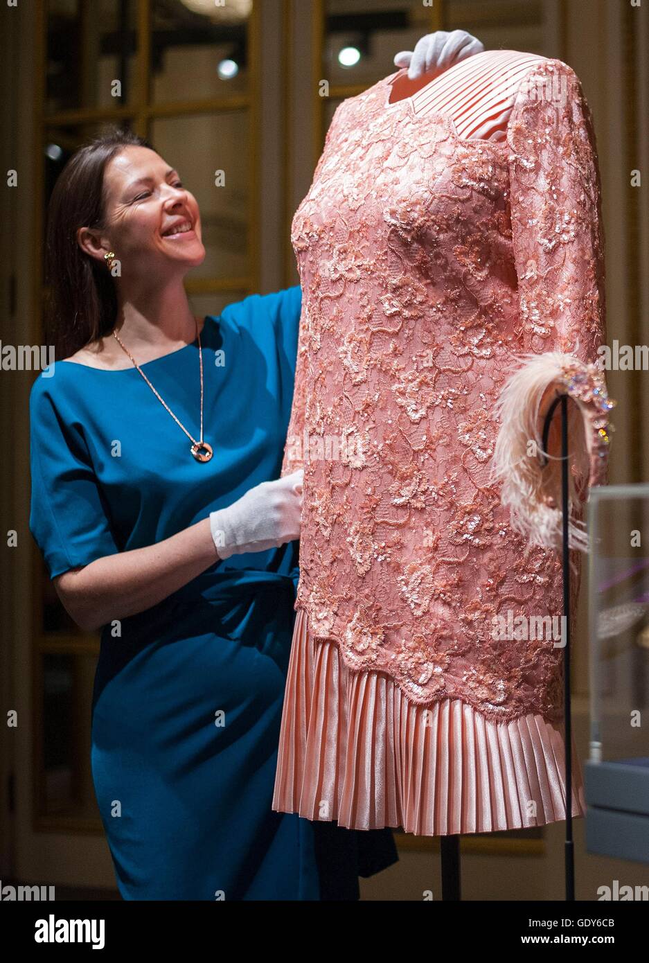 Embargoed to 0001 FRIDAY 22 JULY 2016. Curator Caroline de Guitaut adjusts a peach cocktail dress designed by Angela Kelly and worn by Queen Elizabeth II, at the opening Ceremony of the London 2012 Olympic games, during a press preview for Fashioning a Reign: 90 Years of Style from The Queen's Wardrobe, an exhibition at Buckingham Palace in London. Stock Photo