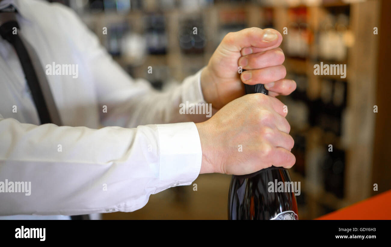 Sommelier uncorks a bottle of sparkling wine in a wine shop. Stock Photo