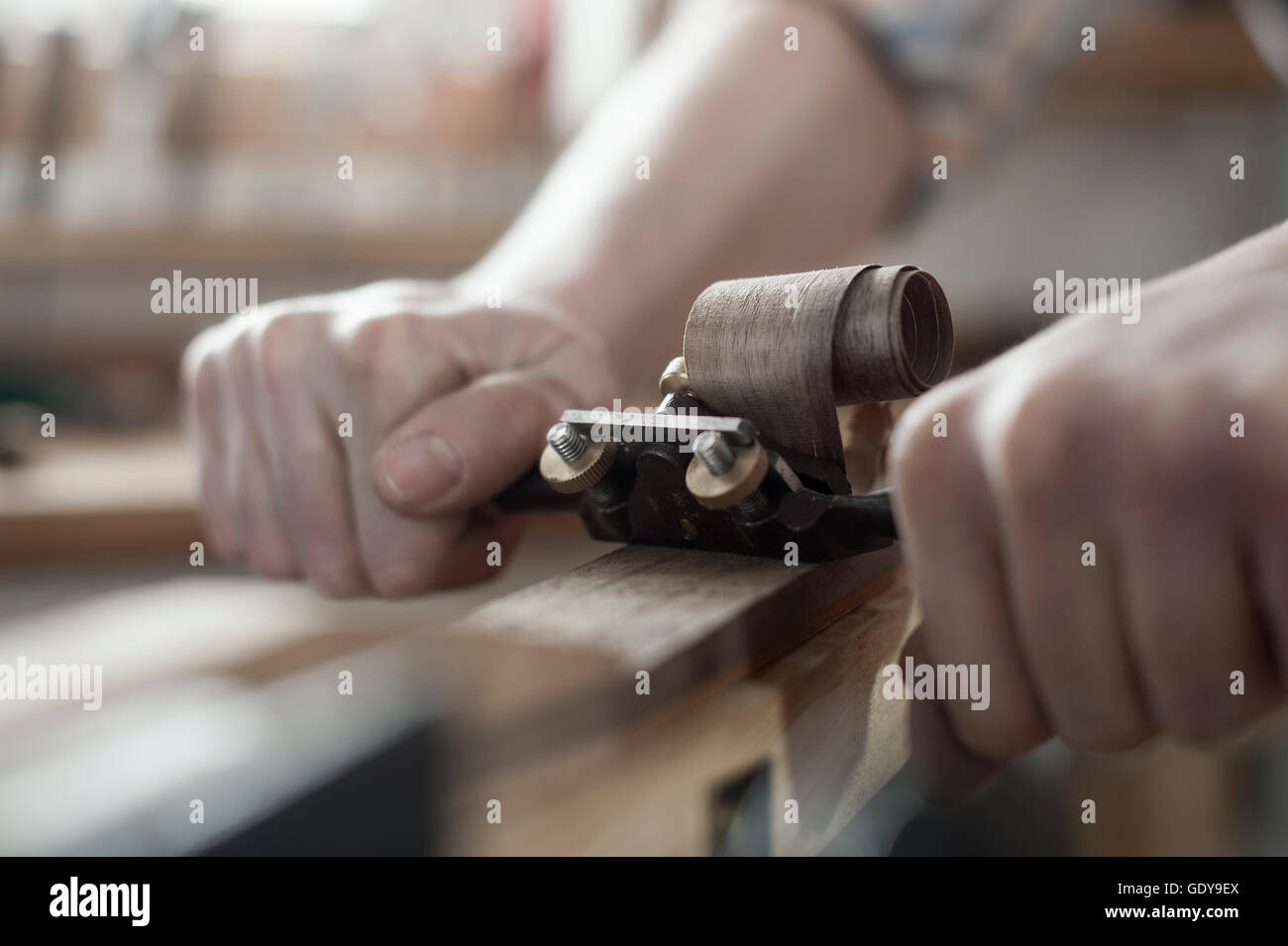 Male bow maker shaving wood and giving it a shape of bow in
