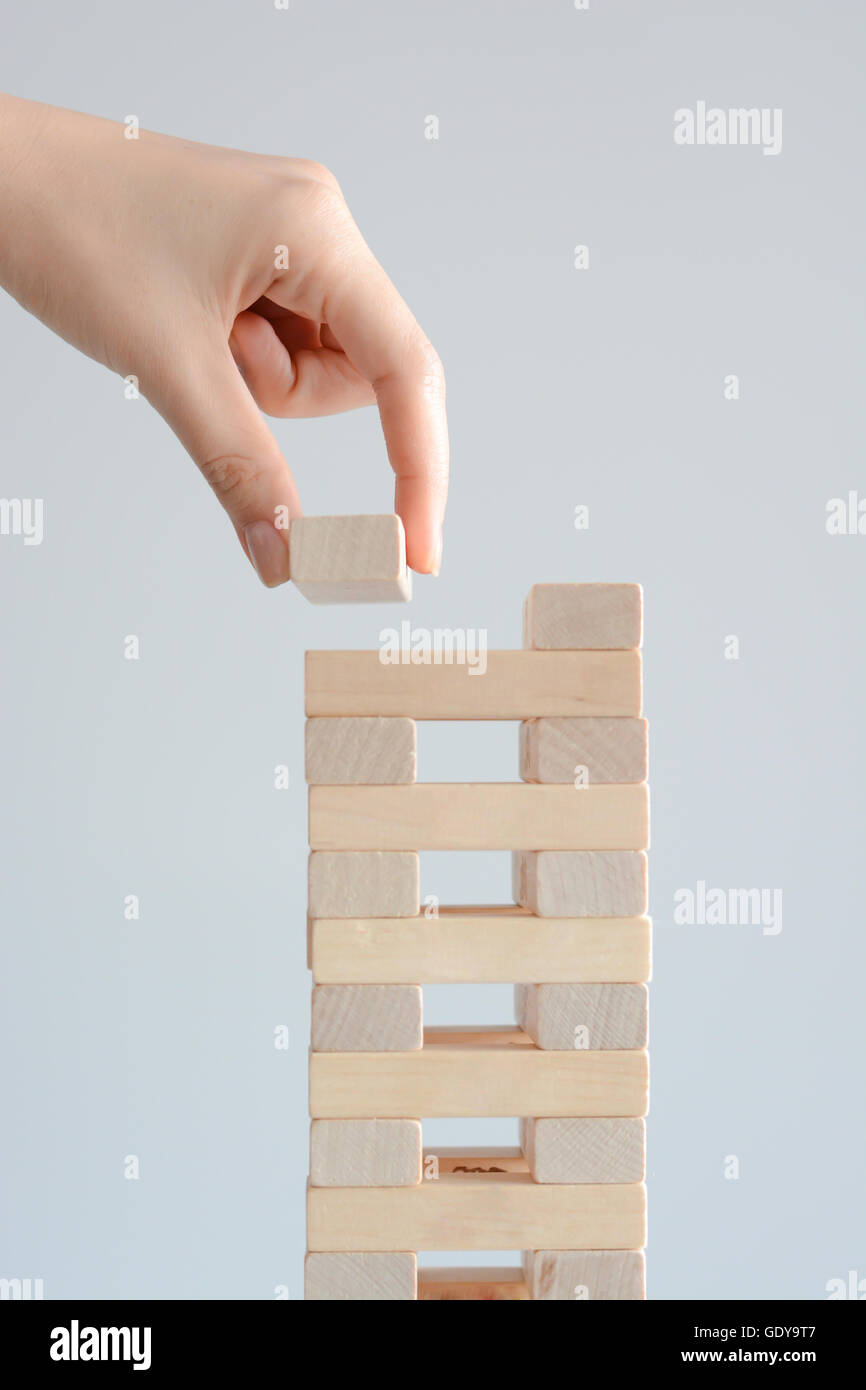 Woman hand constructing a tower of wooden blocks on a white background Stock Photo