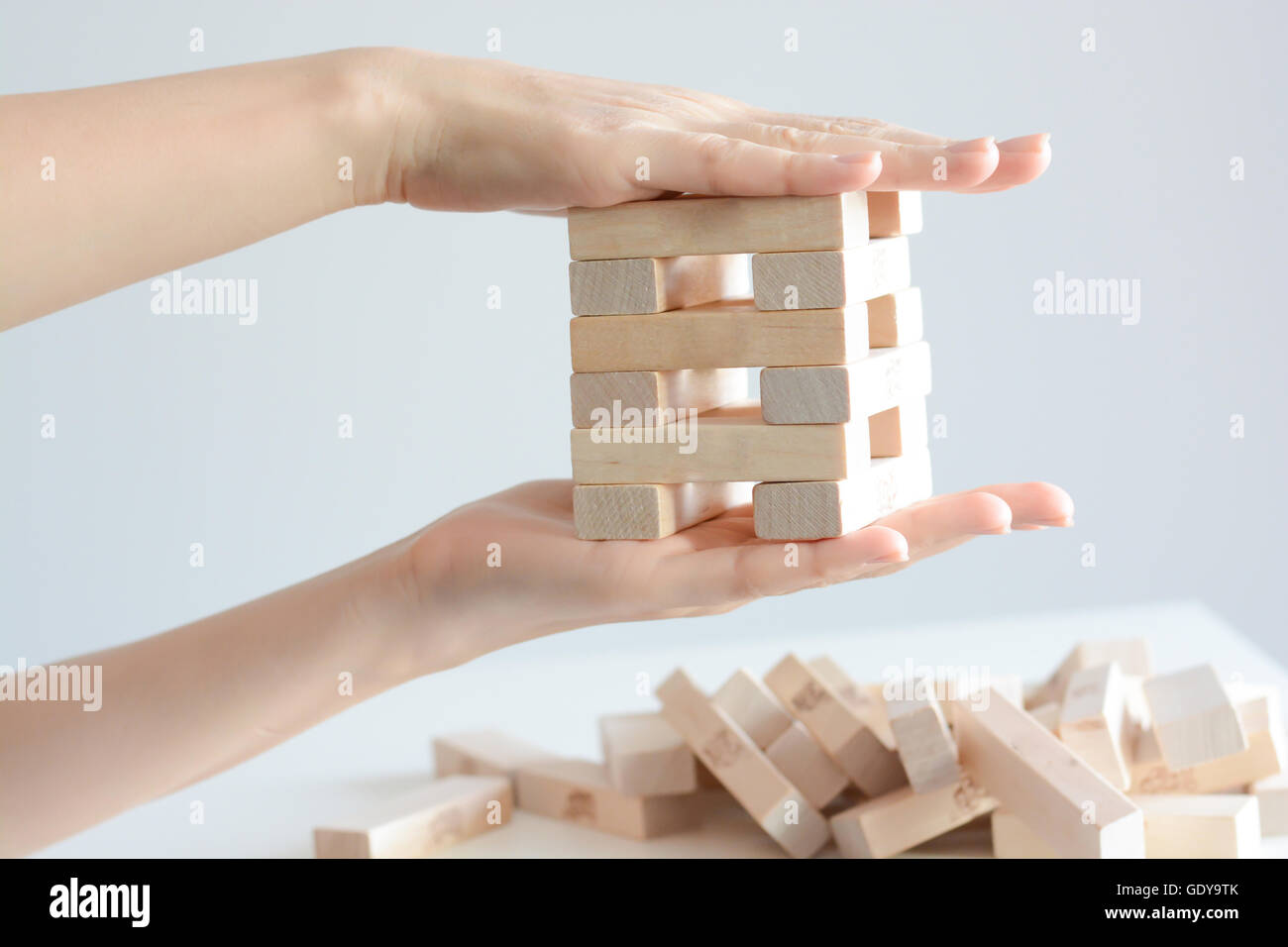 Security or insurance concept with hands protecting construction made from wooden blocks Stock Photo